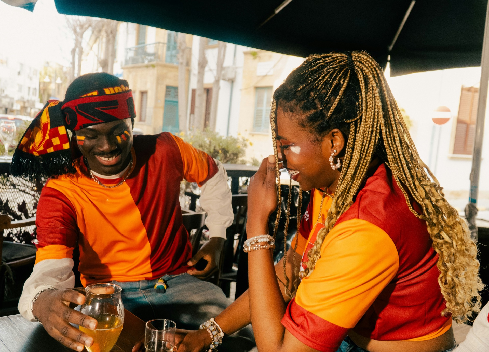 A smiling woman with braids sitting outdoors with a friend